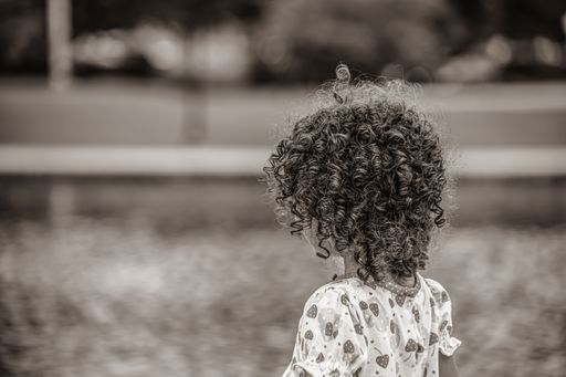 A grayscale shot of little girl with curly hair
