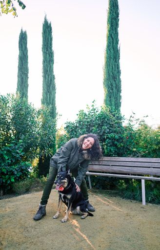 A young caucasian female stroking her dog in the park - Concept of friendship, happiness, company
