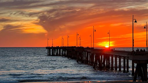 Colorful sunset lights up the beach, pier and ocean in Los Angeles
