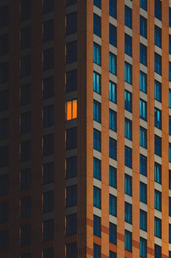 An apartment complex at night, the top floor illuminated by a single blue window