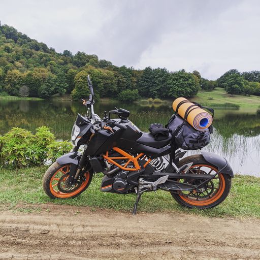 A KTM bike with a strapped bag and yoga mat parked near a lake in Dsegh, Armenia