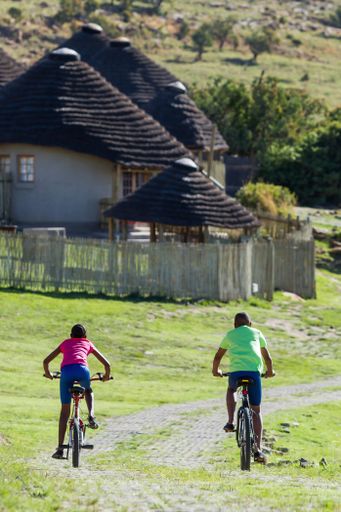 A back view of two African kids riding bicycles heading home