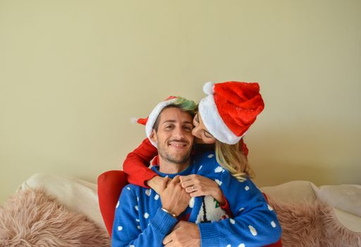 A young happy couple posing in Christmas sweaters and Santa's hats enjoying the holiday mood