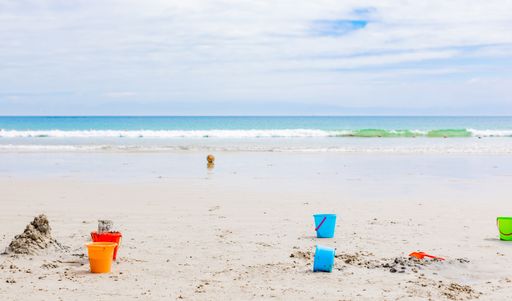 A selective focus shot of several buckets on the sandy beach