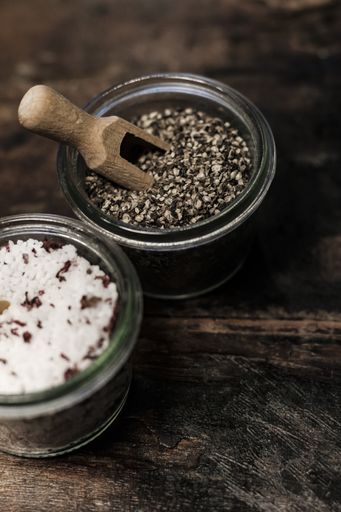 A vertical high angle shot of two glass bowls with seeds on a wooden table