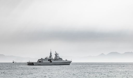 A wide shot of a ship sailing on the water on a cloudy day