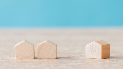 A selective focus of wooden house miniatures on blue background