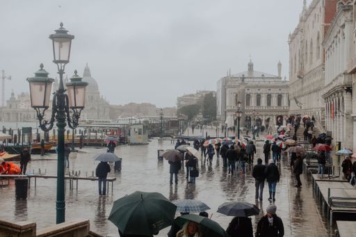 The group of people walking with umbrellas on a rainy day in Venice