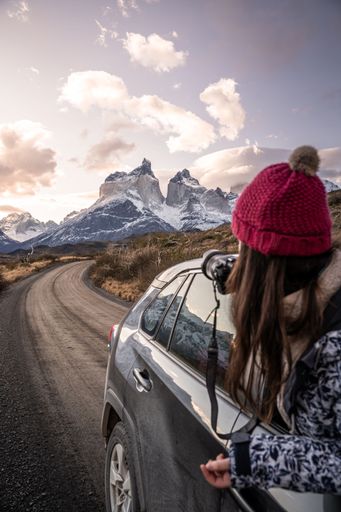 A vertical shot of a Caucasian young female looking from the window to the snowy mountains