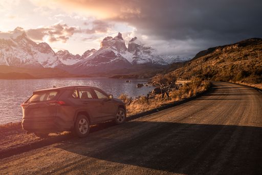 A car parked on a dirt road with the Torres del Paine in the background