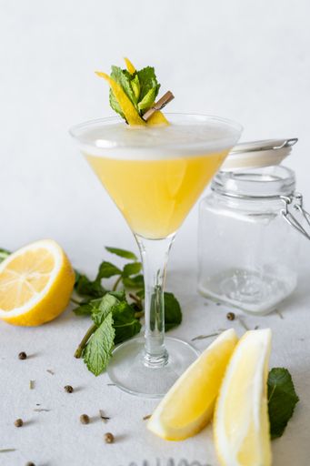 A vertical shot of a refreshing drink decorated with lemon peel and mint leaves
