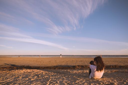 A female sitting on the sand and enjoying the beautiful breathtaking clouds in the sky