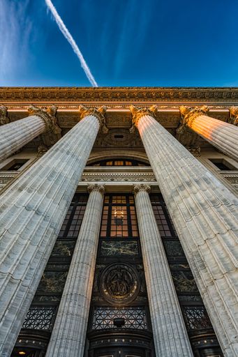 A low-angle shot of an exterior view of a large stone building illuminated by the setting sun