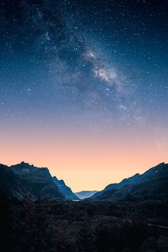 A vertical shot of the mesmerizing starry sky over the hills at sunset
