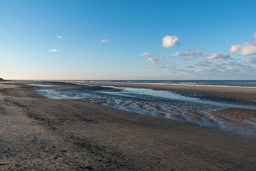 A cloudy sky over a sandy empty beach and a wavy seascape view in Norderney, Germany