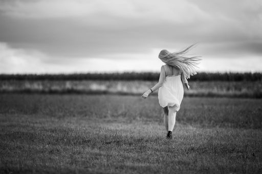 A grayscale shot of a female running in the field