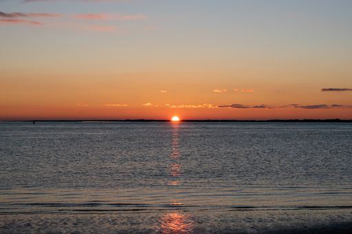 A calm seascape view with a setting down sunset sun on the horizon in  Norderney, Germany
