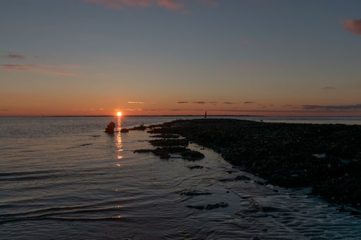 A calm seascape view with a setting down sunset sun on the horizon in  Norderney, Germany