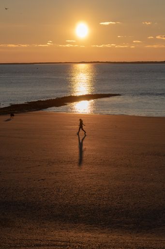 A majestic shot of a brightly shining sunset sun with a reflection on calm seawater in Norderney, Germany