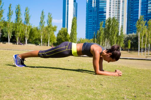 A fit young Latin woman doing a plank and training in the park