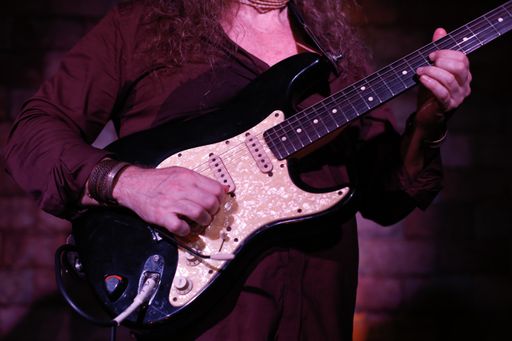 A closeup shot of a musician playing an electric guitar