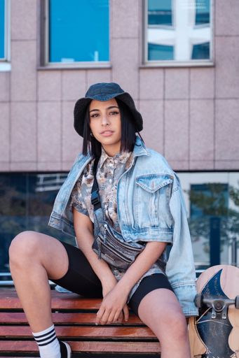 A Young Latina woman wearing a black hat posing in front of a camera