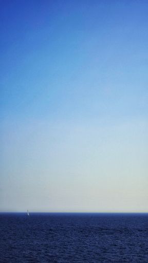 A vertical shot of a ship sailing over the calm ocean