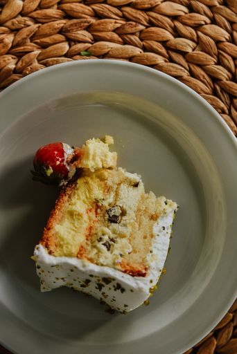 A vertical overhead shot of a slice of a cake with strawberry on the si