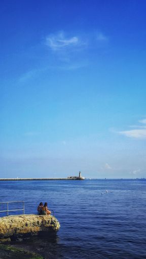 A vertical shot of a lighthouse at the ocean shore under the clear sky