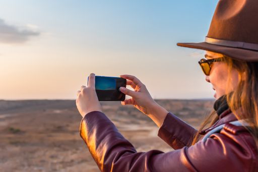 A shallow focus closeup of a female taking pictures using her mobile phone in a natural park- concept travel, lifestyle, and tourism