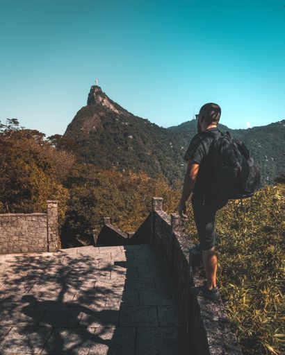 A guy with a backpack watching Christ the Redemeer in Rio de Janeiro over Tijuca National Forest Park.