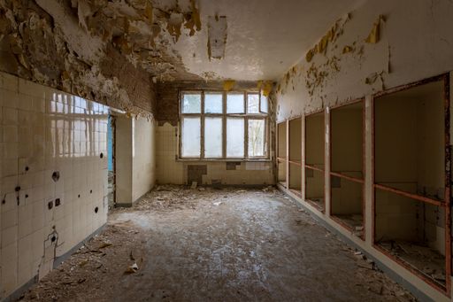 A view looking down the corridor into an abandoned building with paint smeared on the walls