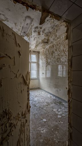 An empty room with peeling paint and a window in it in an abandoned building