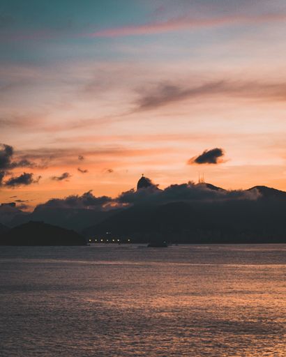 A breathtaking sunset over the ocean and the silhouette of the statue of Christ the Redeemer in Rio de Janeiro