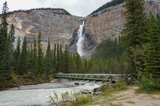 A river and a bridge in the foreground, contrasted by the large waterfall in the background- in British Columbia, Canada.