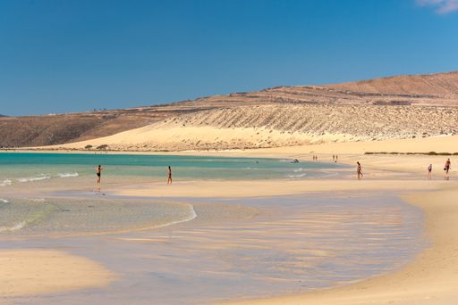 Sotavento, Fuerteventura, Spain: 2020 October 8: Young Blonde Woman walks through the dunes at Playa de Sotavento, Fuerteventura in Spain in summer.