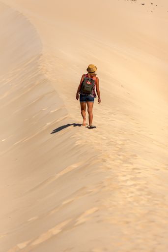A young blonde woman walks through the dunes at Playa de Sotavento in Fuerteventura, Spain