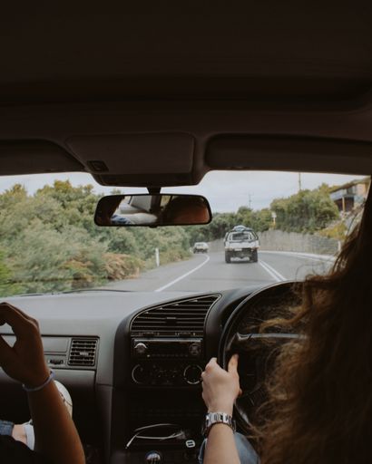 A female driving a car with her friend sitting next to her shot from inside