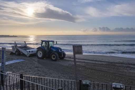 A shot of a standing tractor on the seacoast at the sunset time under a cloudy sky
