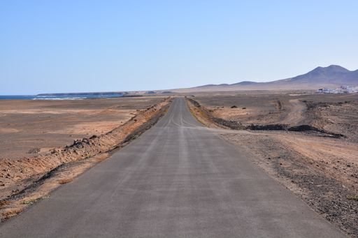 A view of a countryside desert dirt road on a clear sky bac