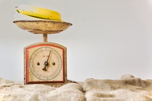 Bananas on a vintage and retro weighing scale with white background and copy space. Fruit balance