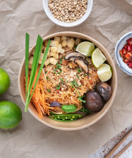 A vertical shot of a serving of delicious noodles with salads, lime, greens, buckwheat, and crumbs