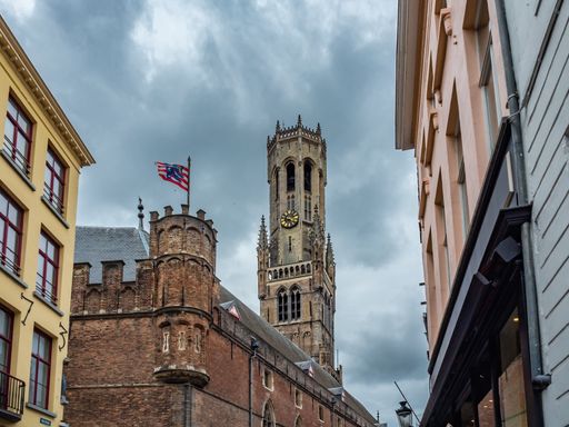 A low angle shot of Bruges flag with Belfort tower background