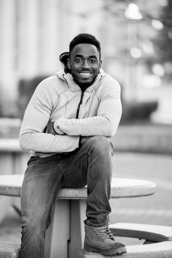 A vertical greyscale shot of an attractive African American male smiling at the camera
