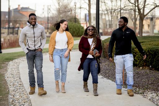 A group of friends walking happily on the sidewalk in a park