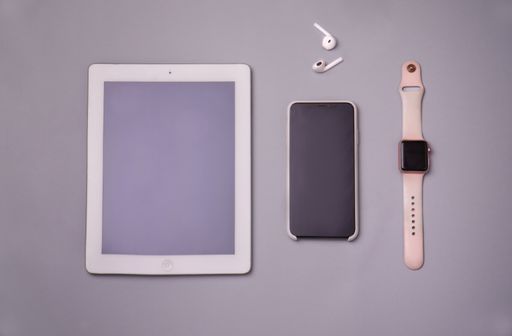 A high angle shot of a tablet, a cellphone, a smartwatch, and earphones