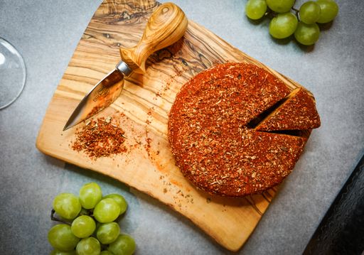 A top view of a pastry cut in a slice decorated with green grapes on a wooden board