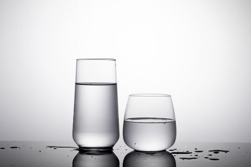 A shot of two glass of water -  highball glass and whiskey glass on the white surface with shadows