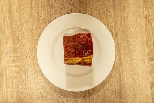 A high angle shot of a slice of raw meat on a wooden board