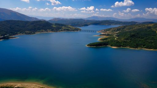 An aerial shot of the Campotosto Lake in Abruzzi, Italy with a bridge over it